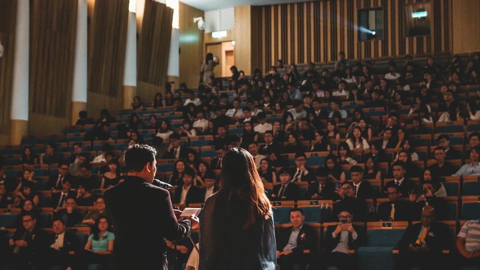 Speakers addressing an audience in a medical education auditorium.